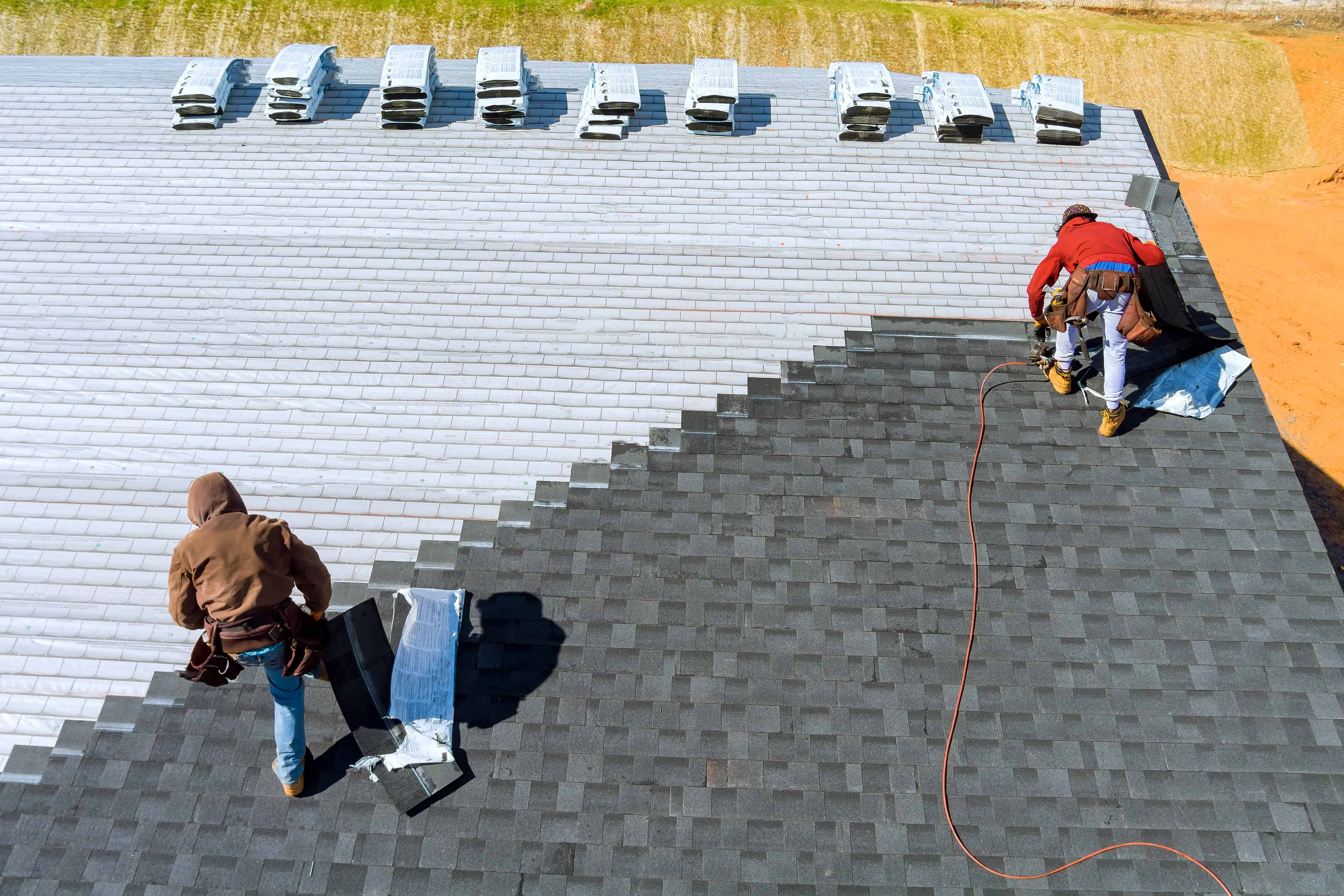 Travailleurs installant des tuiles sur un toit.