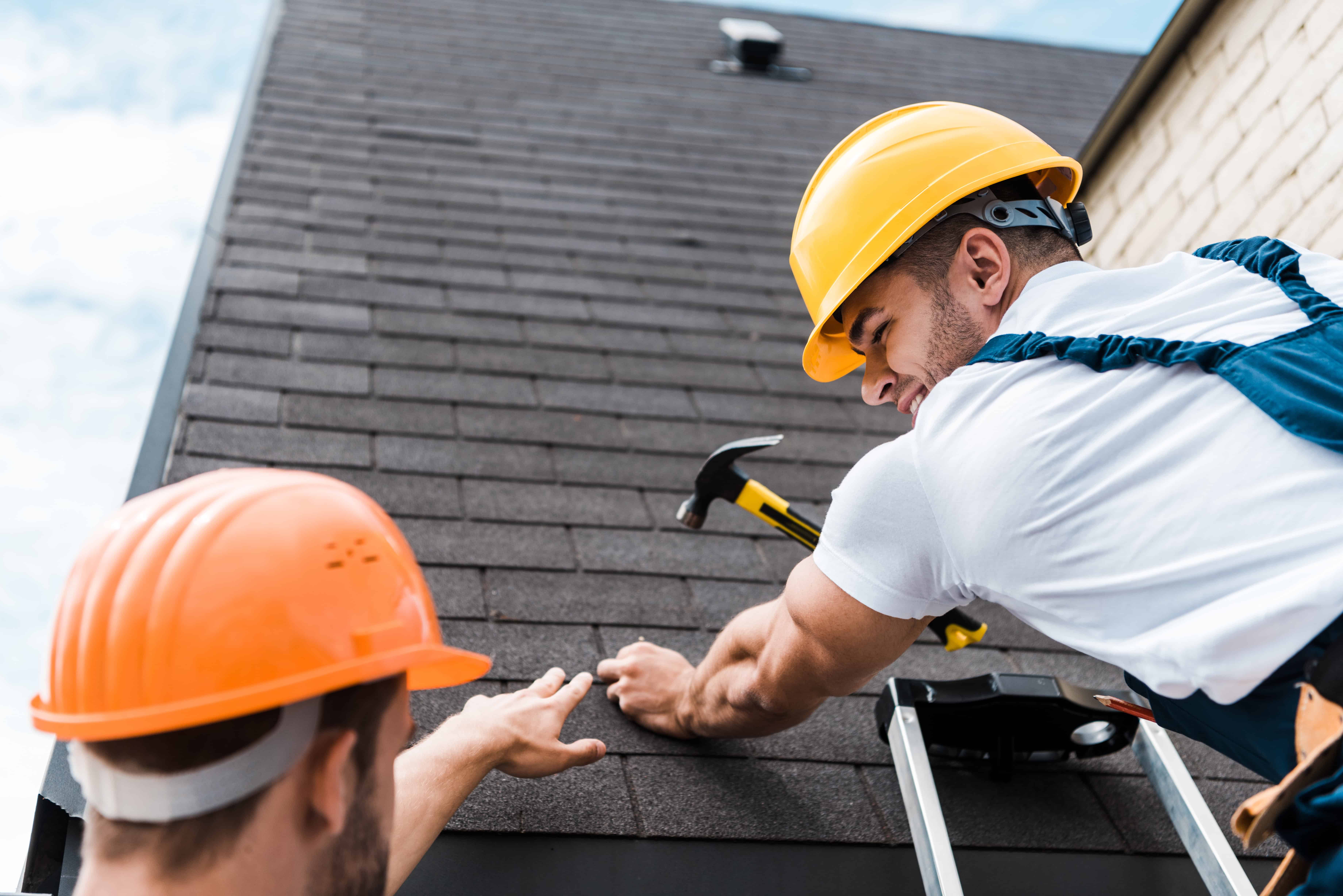 Travailleurs installant un toit en tuiles noires.