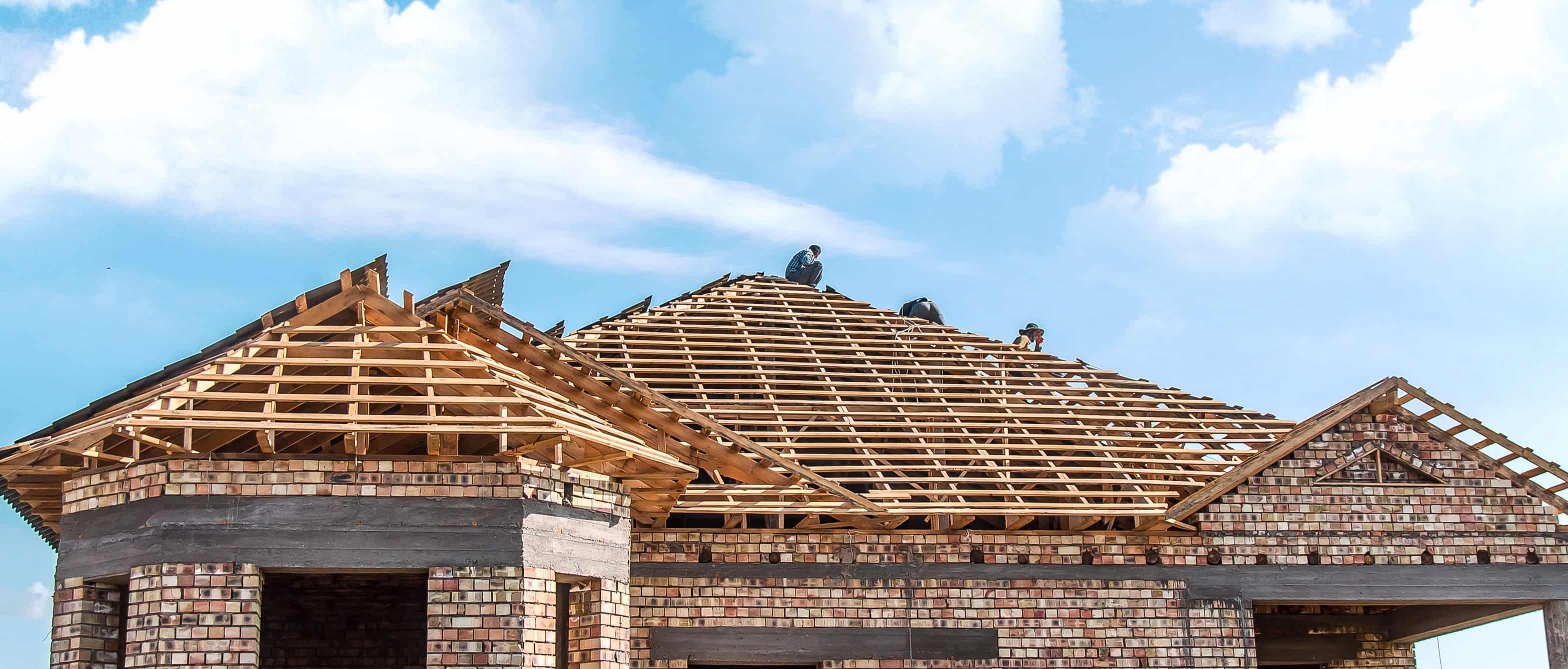 Construction d'une maison en briques avec toit en bois.